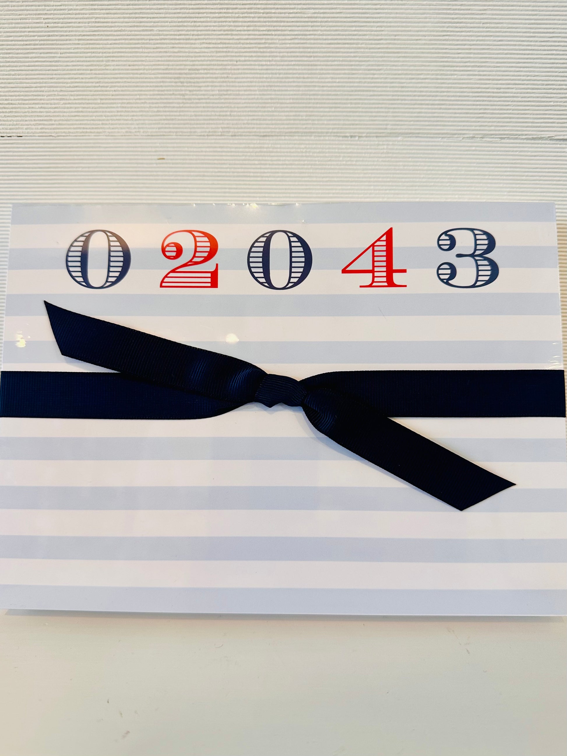 large rectangle notepad with 02043 across top in navy and red.  notepad paper had light blue and white stripes