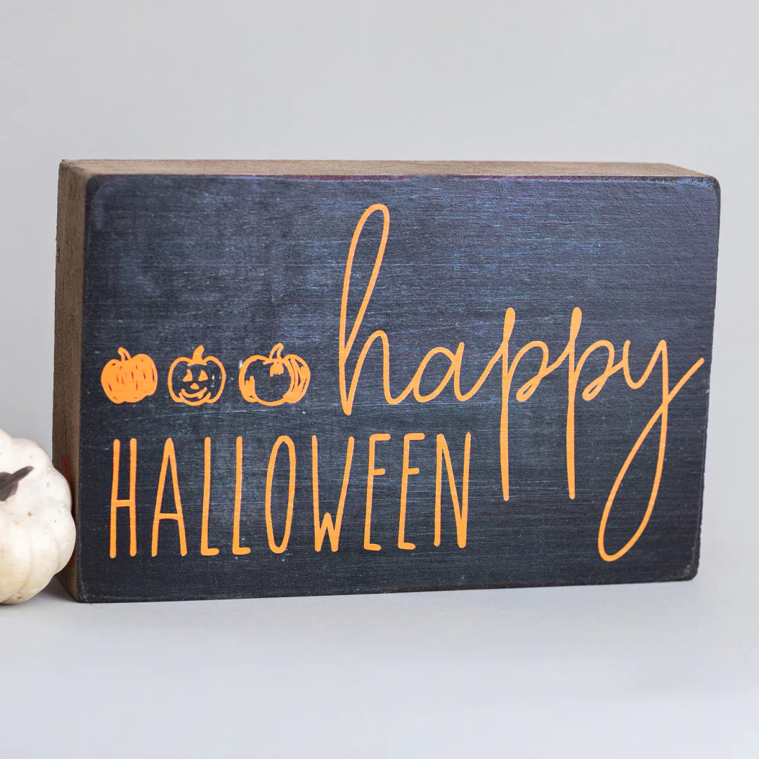 wooden block with black background and happy halloween in orange writing