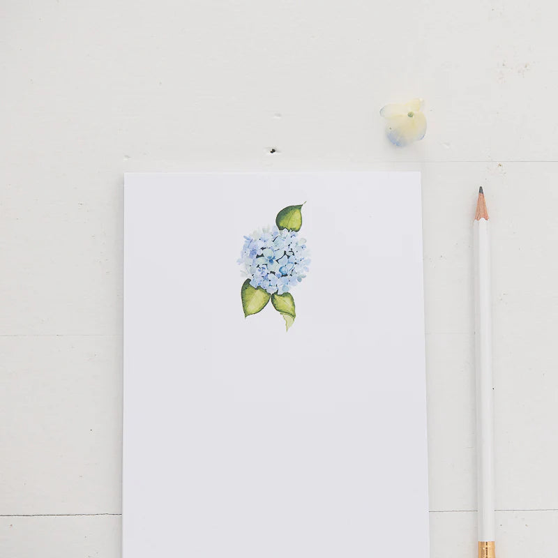 White notepad with a blue hydrangea flower at the top center
