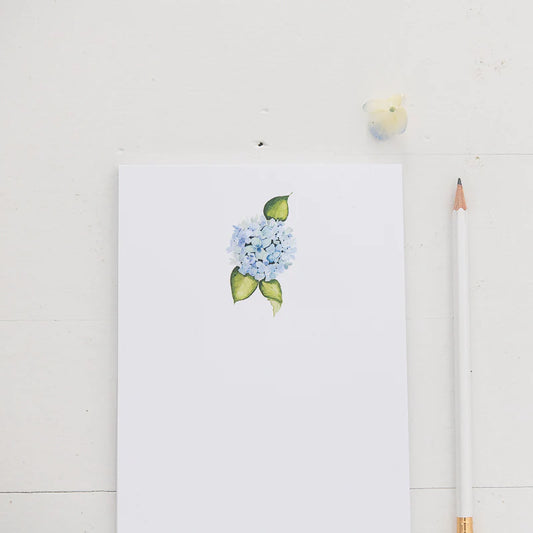 White notepad with a blue hydrangea flower at the top center