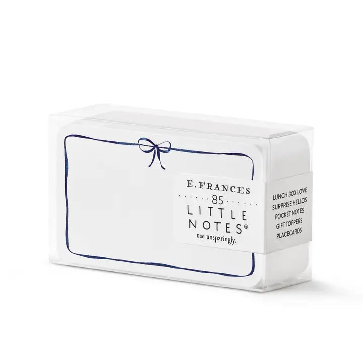 Small white note cards with a navy blue border that has a bow on the top middle.