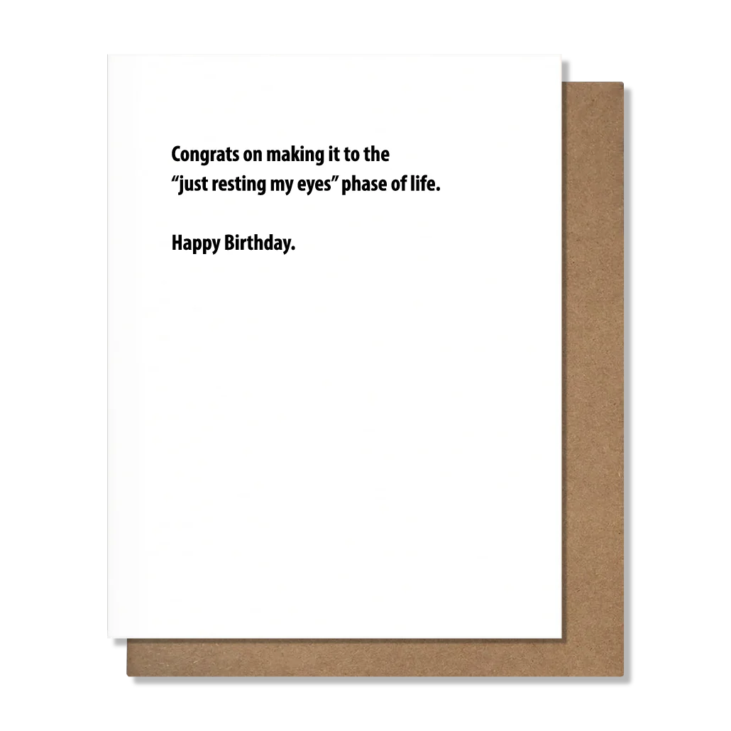 A2 size birthday card with a blank inside, featuring a textual message that reads 'CONGRATS ON MAKING IT TO THE JUST RESTING MY EYES PHASE OF LIFE. HAPPY BIRTHDAY!' and a kraft envelope.