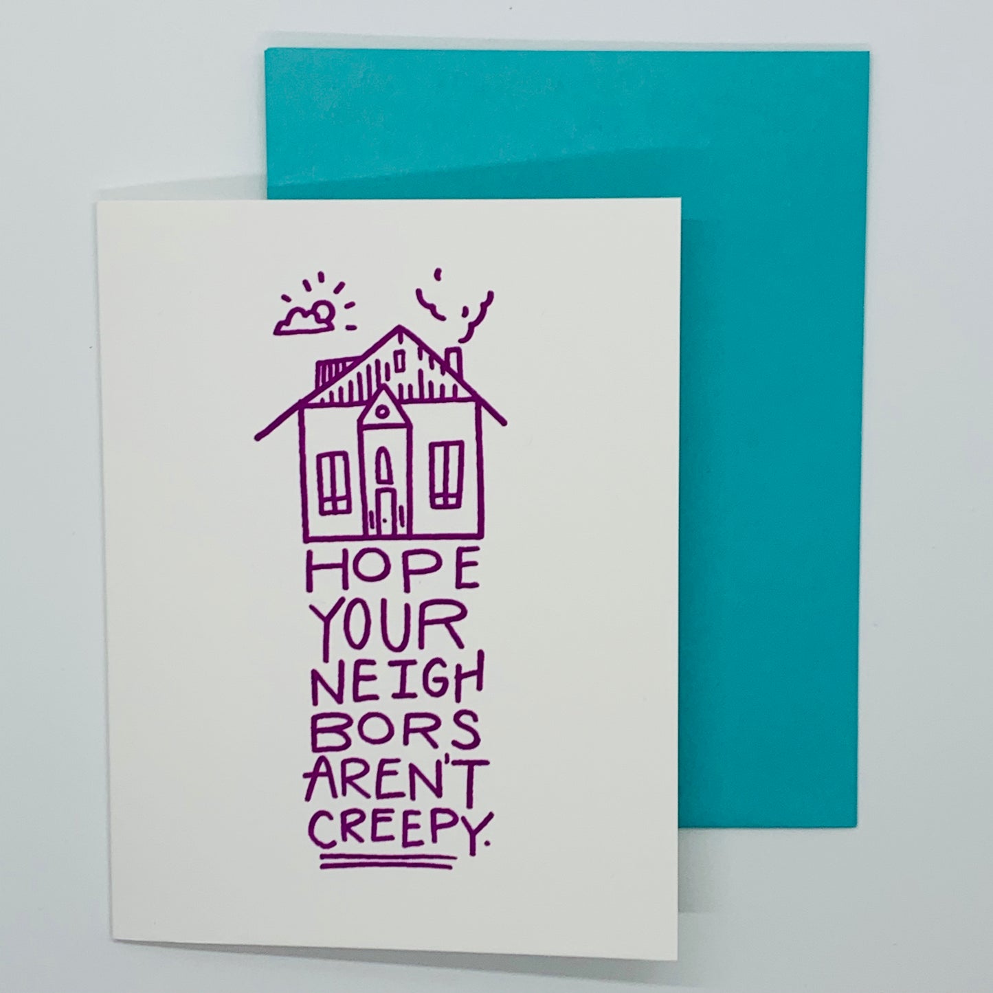 White greeting card that states 'Hope your neighbors aren't creepy' with teal envelope