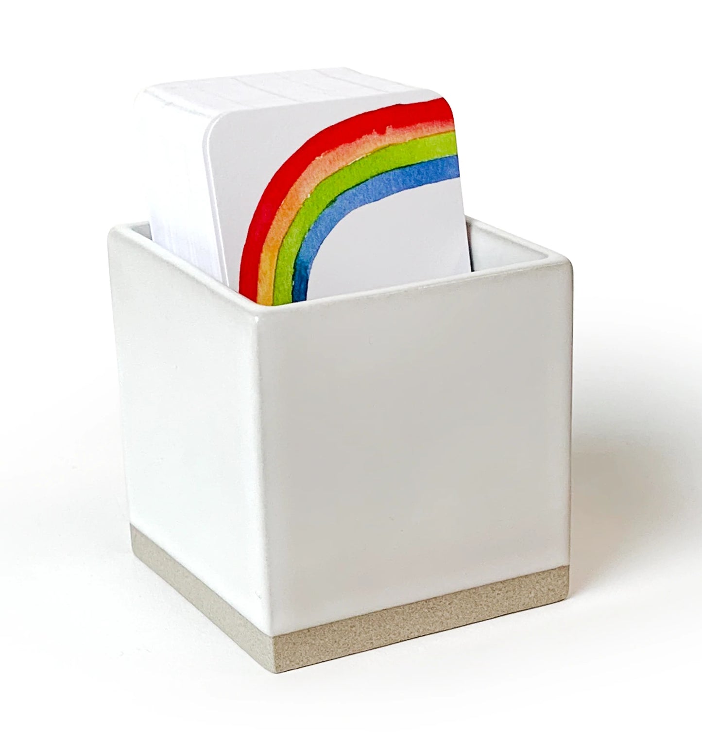 A ceramic Little Notes notecard holder with a white exterior and beige base, containing multi-colored rainbow Little Notes note cards.