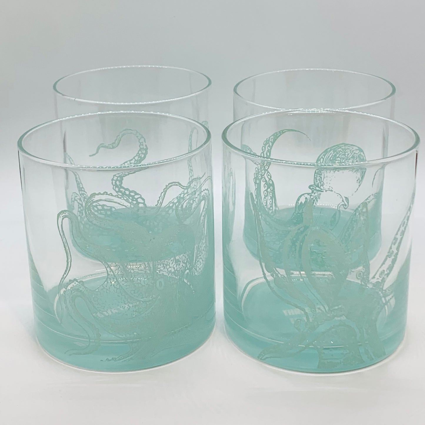 Teal and clear glasses with octupi on them and a teal base