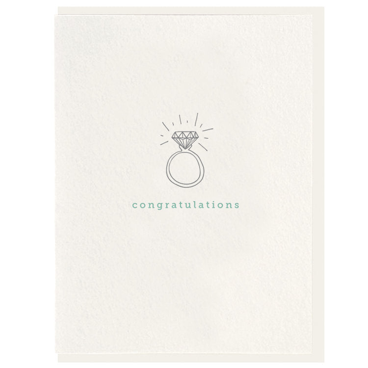 White card with gray wedding ring in the middle that has teal writing under it.
