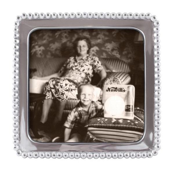 A silver beaded square picture frame with a 5x5 opening displaying and a black and white photo of a woman and a child