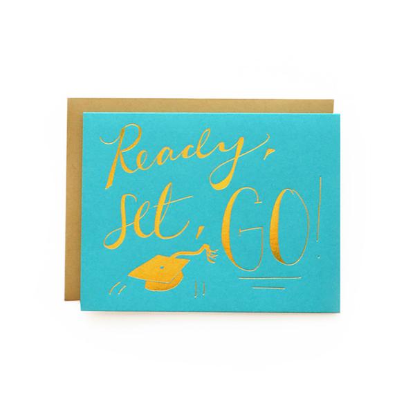 A greeting card with a blue background and the text 'Ready, Set, Go!' in yellow. There is a graphic of a graduation cap and the graduation phrase 'Go, graduate!' on the front.