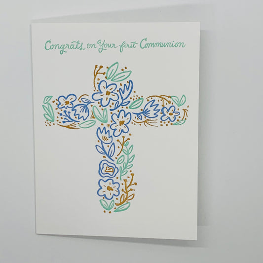 white card with congrats on your first communion in mint green.  a cross with blue, green, gold flowers