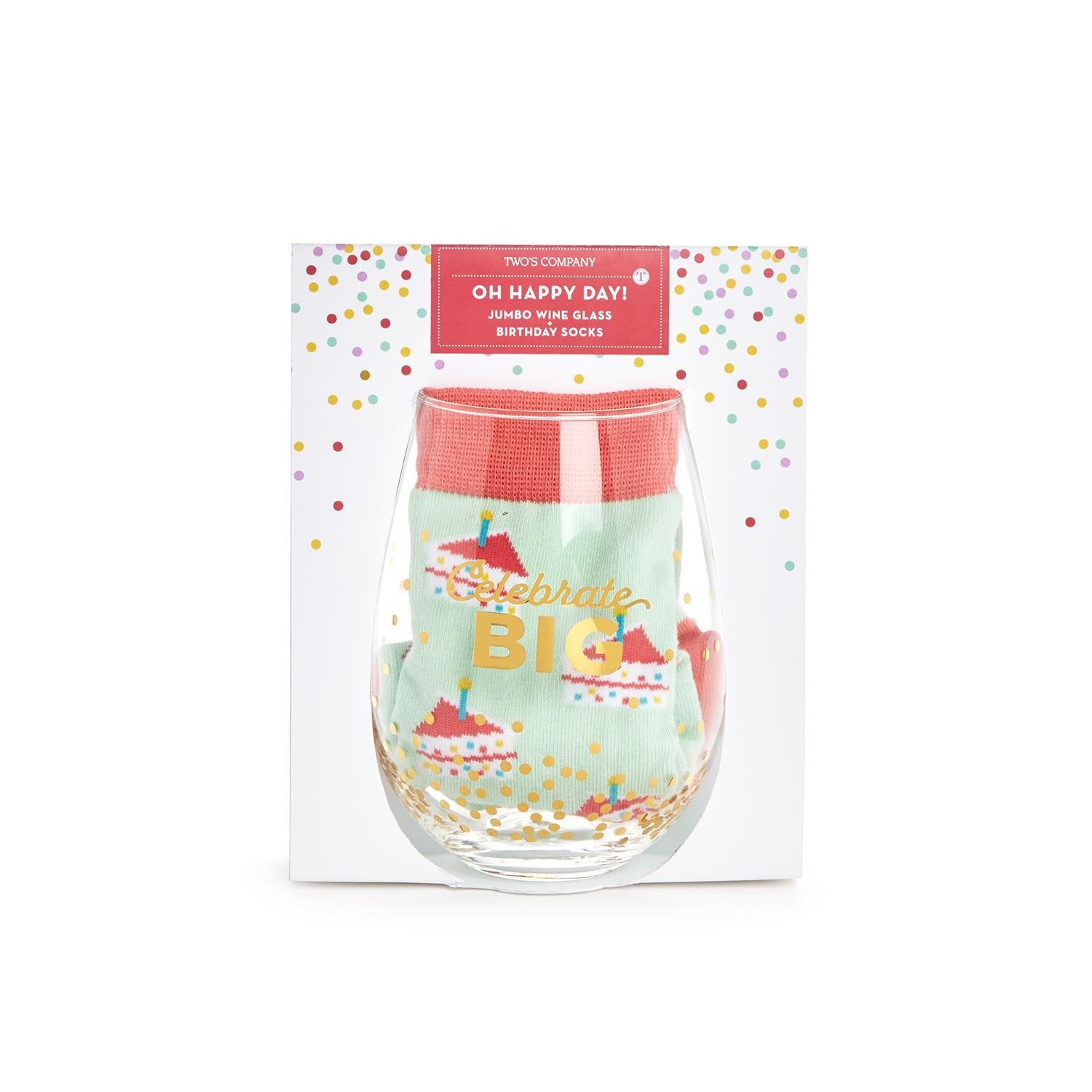packaged Jumbo stemless wine glass with OH HAPPY DAY and gold text on the glass that reads "celebrate big" also included in the glass is a pair of birthday socks in mint green with slices of birthday cake  and candle design on them  