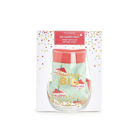 packaged Jumbo stemless wine glass with OH HAPPY DAY and gold text on the glass that reads "celebrate big" also included in the glass is a pair of birthday socks in mint green with slices of birthday cake  and candle design on them  