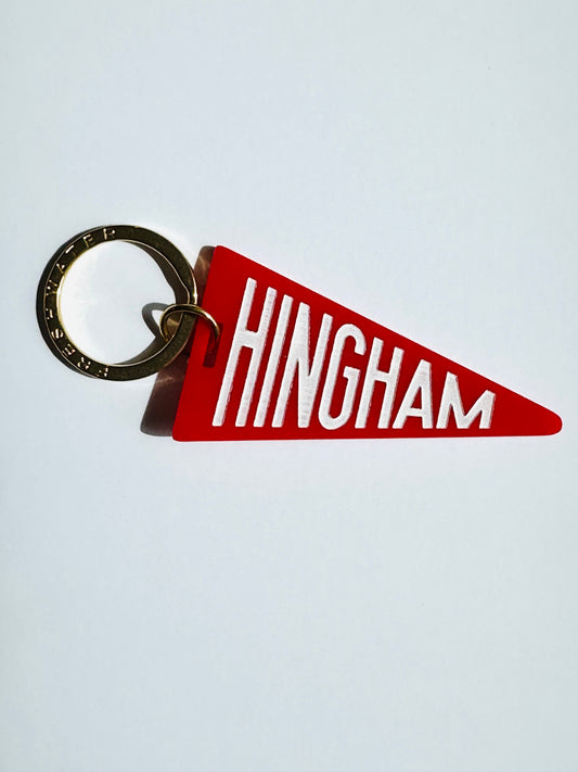 A red triangular pennant keychain with the word 'HINGHAM' in bold white letters, attached to a silver metal split ring, shown against a plain light gray background.