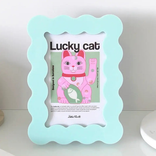 A pastel light blue scalloped picture frame holding a printed card with a pink lucky cat illustration and the words 'Lucky cat'.