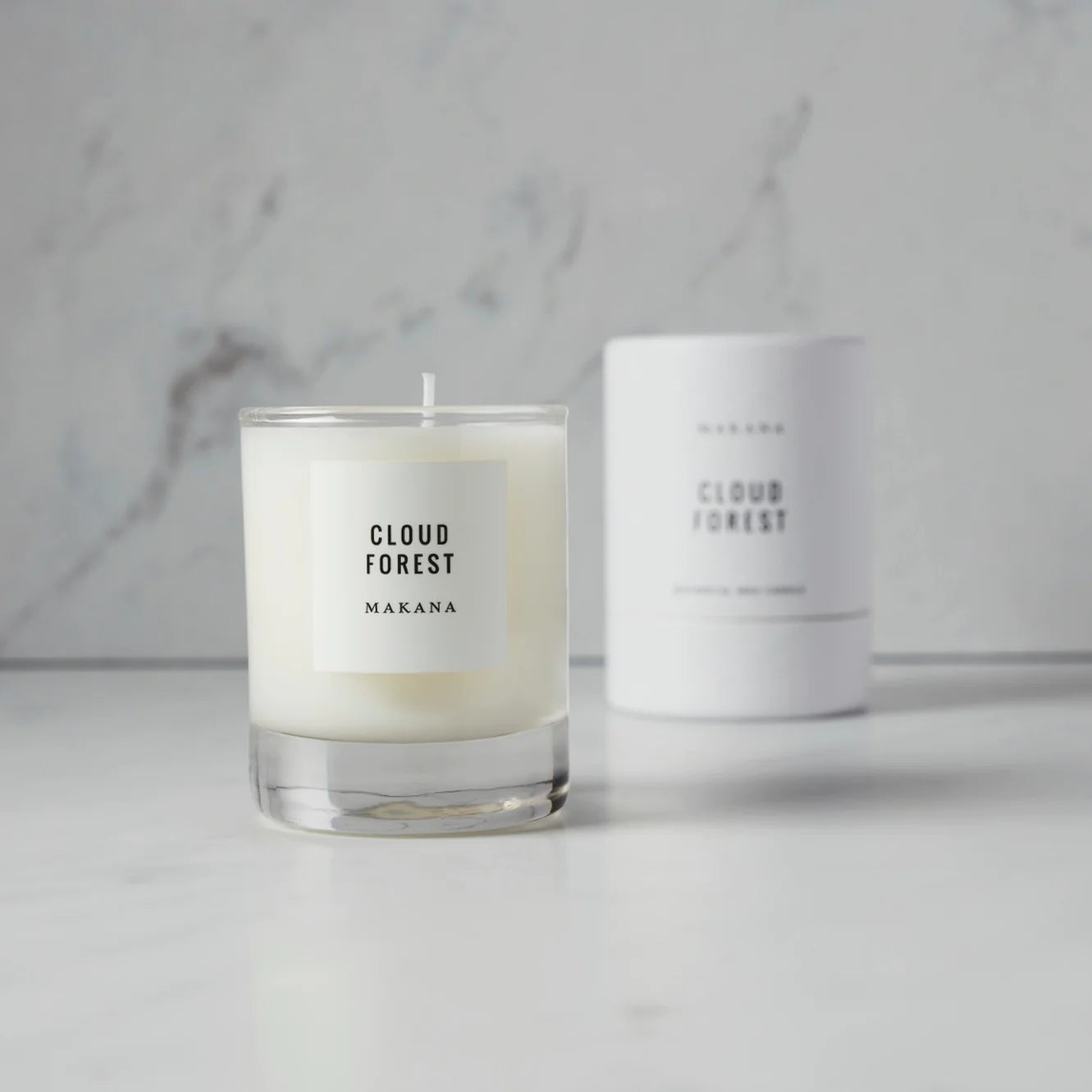 Cloud Forest Candle = glass jar with white label black writing.  packaged candle in background