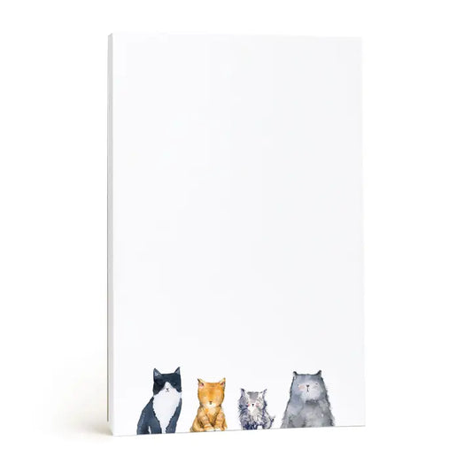 A white notepad or letterhead pad with a watercolor illustration of four cats along the bottom edge, shown standing upright on a white background.