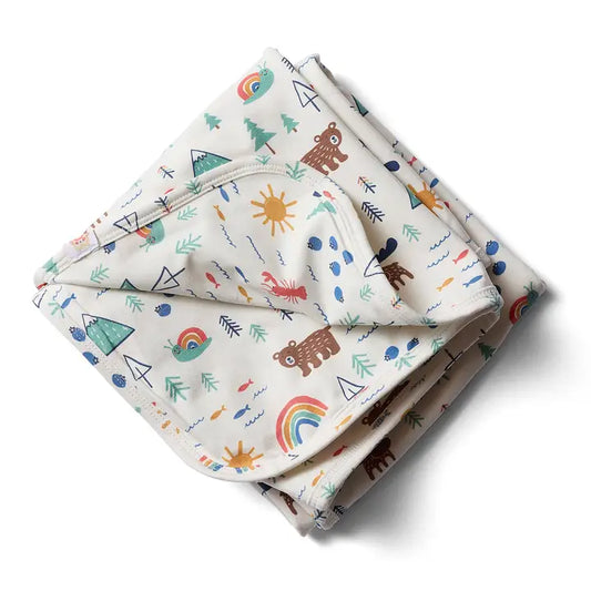 A folded baby blanket with a whimsical outdoor pattern featuring brown bears, evergreen trees, rainbows, lobsters, fish, mountain peaks, and suns on a cream background.