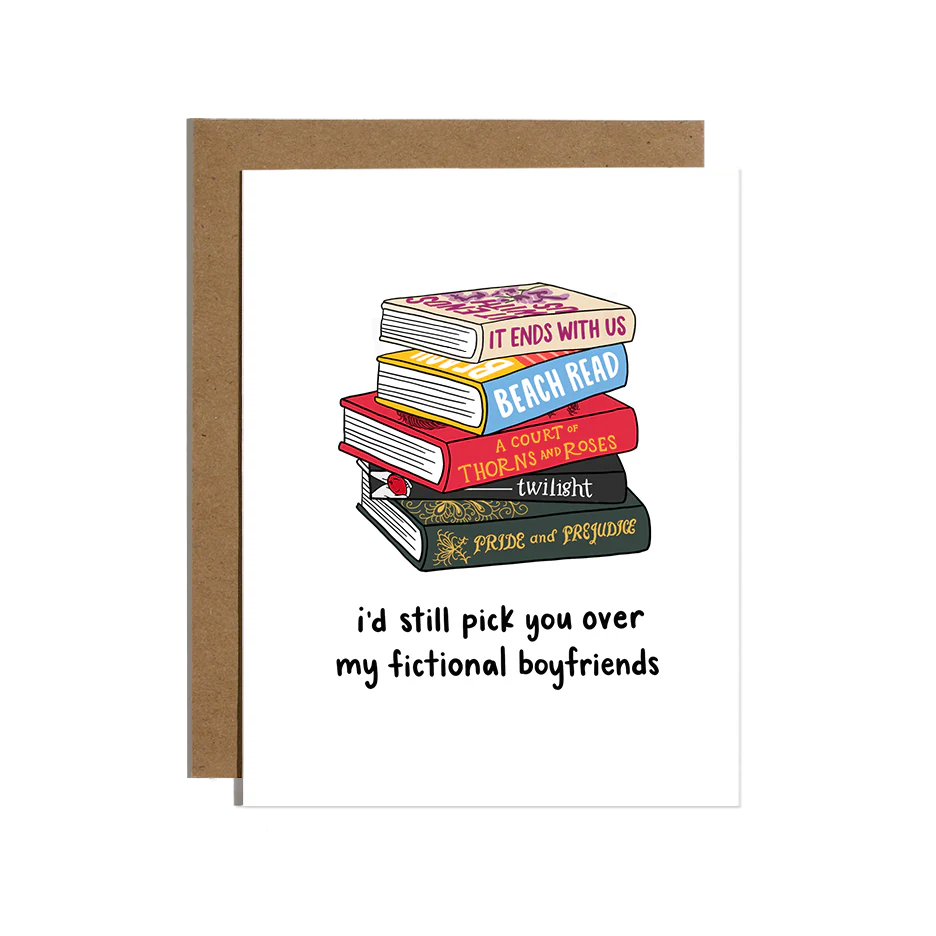 Stack of romance books with 'I'd still pick you over my fictional boyfriends' written below on a greeting card with a brown envelope.