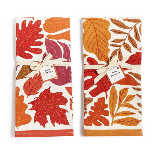 Two folded white dish towels with an autumn leaf pattern, tied with white ribbon 