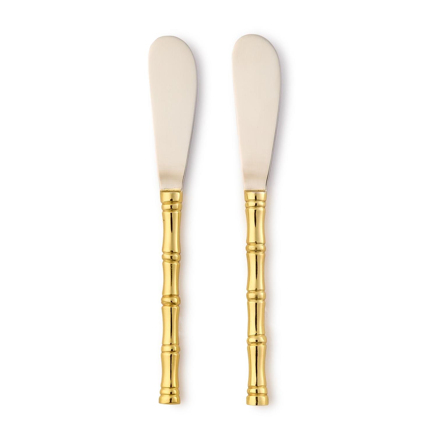 Two spreader knives with gold handles on a white background