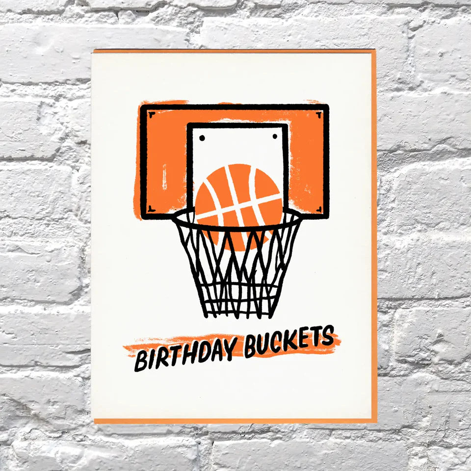 Illustration of a basketball hoop with a ball and 'Birthday Buckets' text on a white brick wall background.