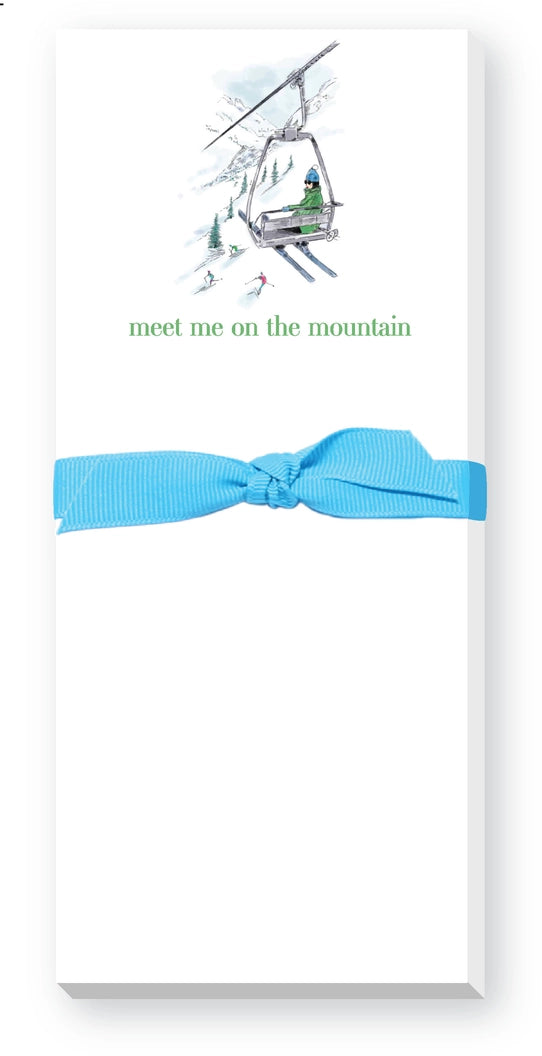 Notepad with a blue ribbon and mountain-themed illustration with the phrase 'Meet me on the Mountain' on a white background