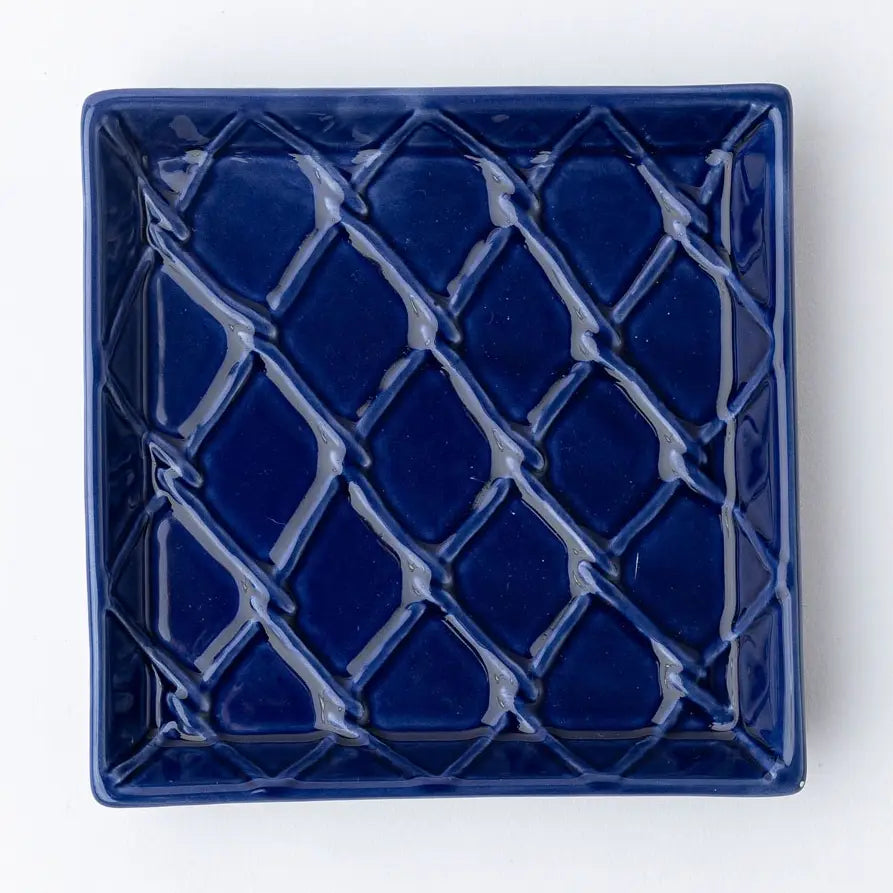 Blue ceramic square napkin holder with lattice pattern on a white background