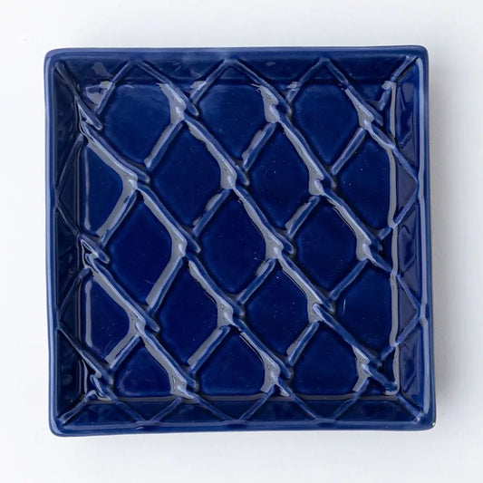 Blue ceramic square napkin holder with lattice pattern on a white background