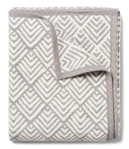 A grey and ivory geometric patterned blanket with a reversible design, folded to show both sides.