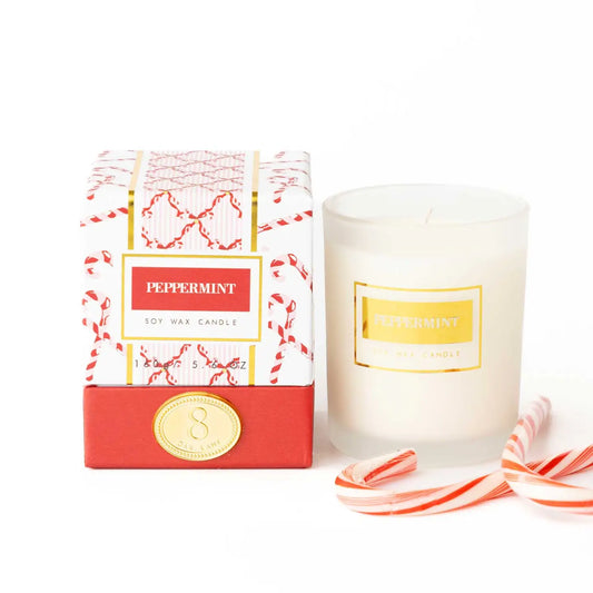 Peppermint candle with packaging and candy canes on a white background