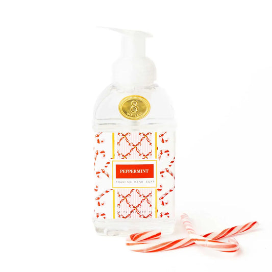 Bottle of peppermint-themed foaming hand soap with candy cane elements on a white background