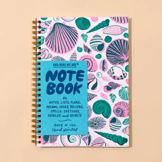 A spiral-bound notebook with a colorful seashell pattern on a white cover.