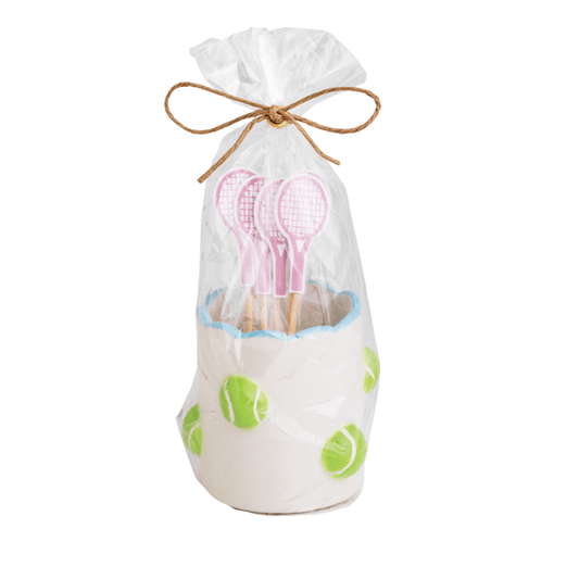 Toothpick holder with pink tennis racket picks in a scalloped edge white ceramic  holder with tennis balls scattered on it in a clear cello bag tied with twine 