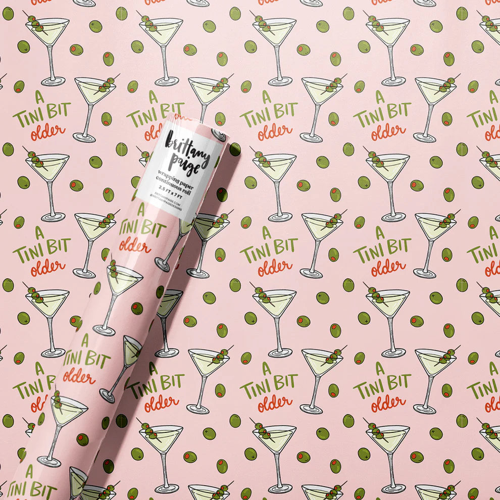 Gift Wrap with 'A Tini Bit Older' text on a pink background with martini cocktail and olive pattern