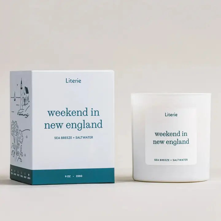 Literie candle in white glass tumbler with "weekend in new england" printed in teal packaging featured in light blue with teal blue strip on bottom sea breeze & saltwater scent