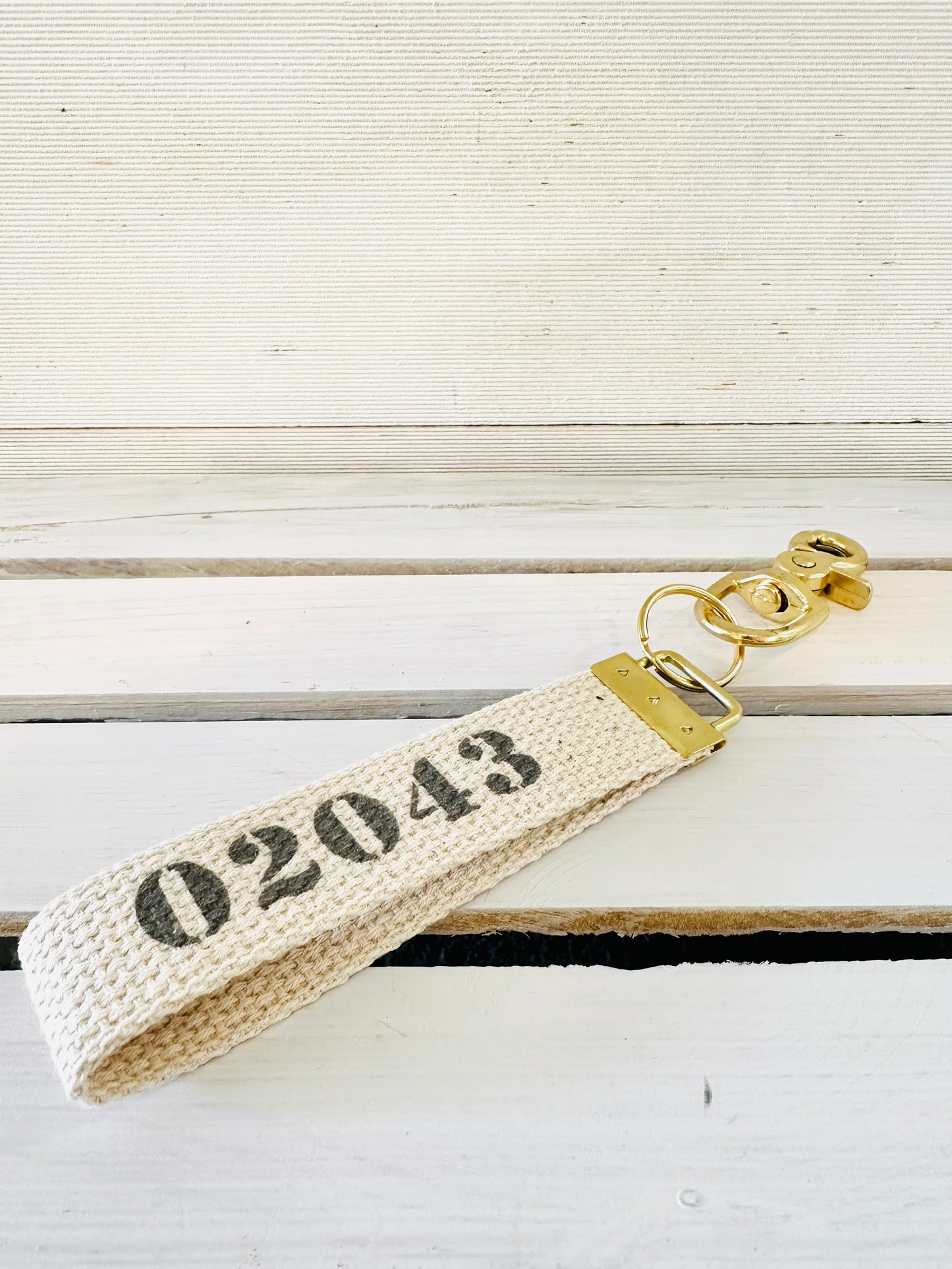 woven keychain with 02043 in gray across center. brass hook