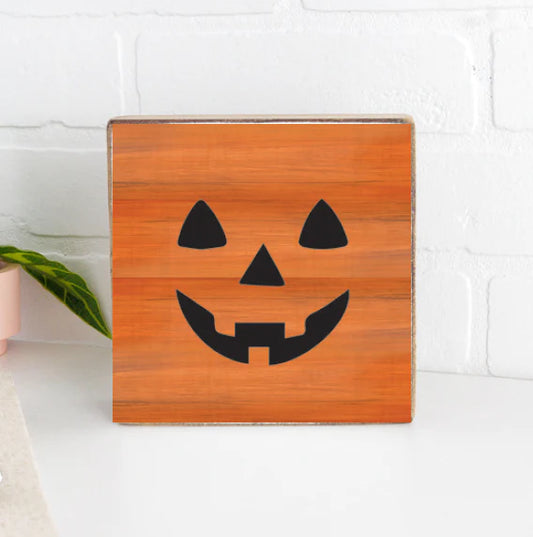 orange wooden block with black jack-o-lantern face