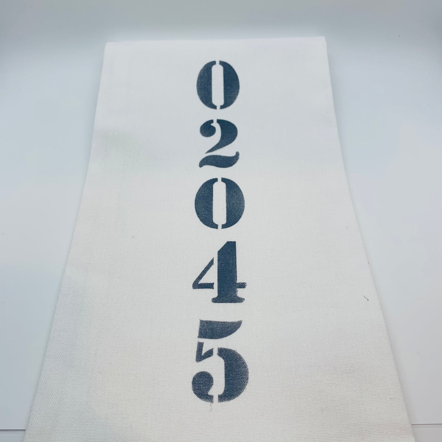 White tea towel with zip code 02045 down the middle in a navy color