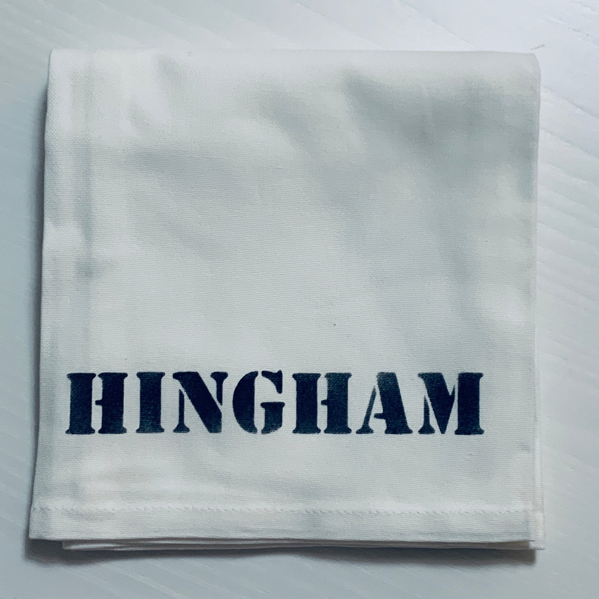 Hingham Tea towel that is white with navy blue writing