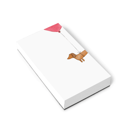 A white notepad with half of a wiener dog that has a balloon tied to its waist illustrated on the right side of the notepad