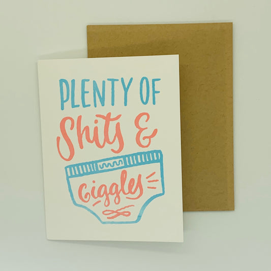 A greeting card with the text 'Plenty of Shit & Giggles' on it, accompanied by a kraft envelope.