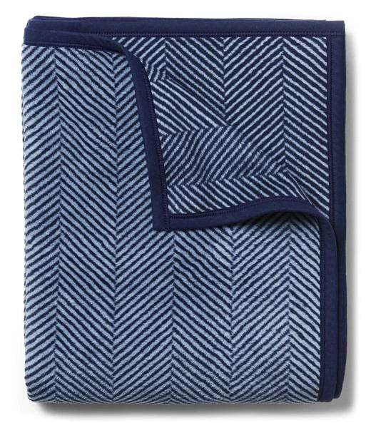 A navy blue herringbone patterned blanket with a soft focus background.