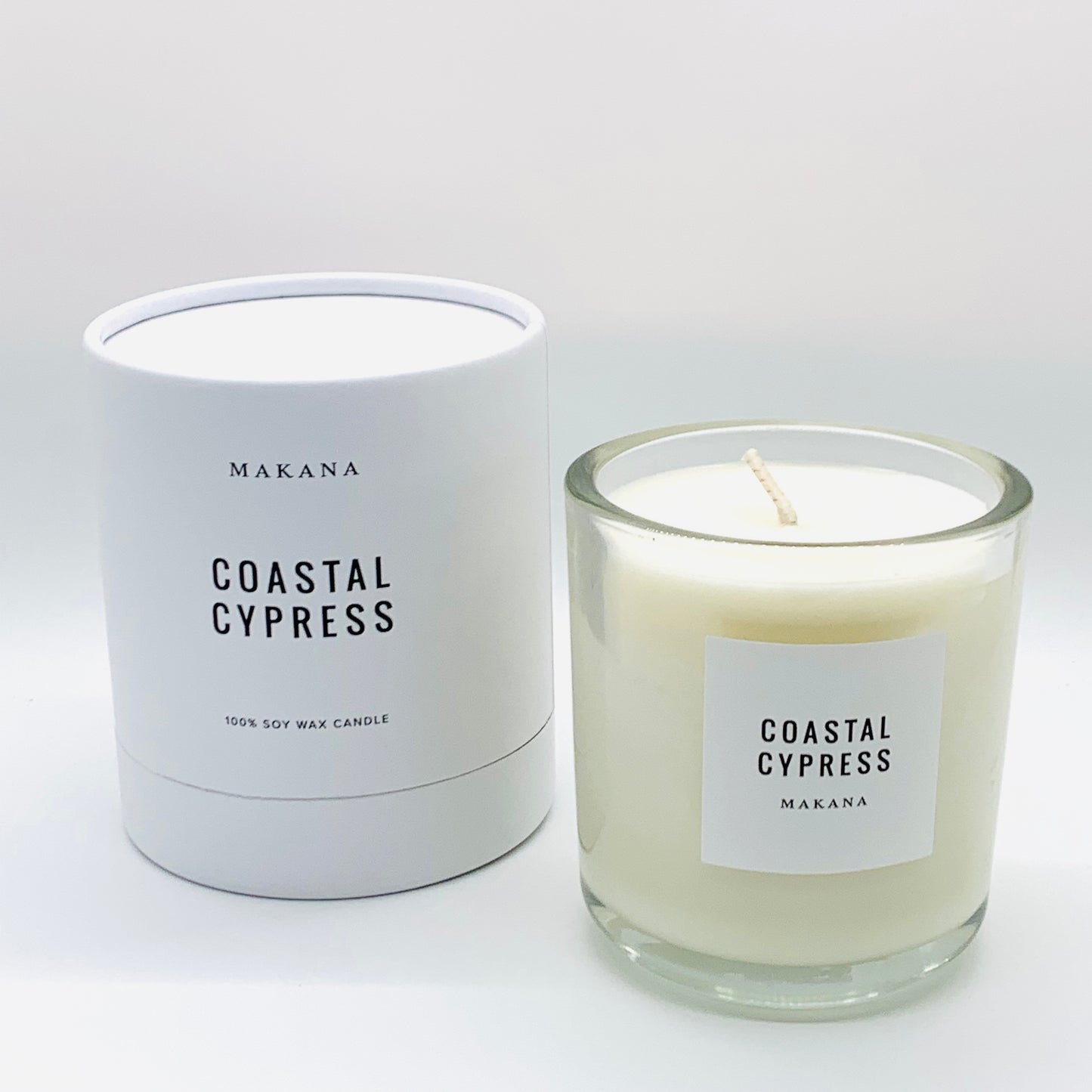 Coastal Cypress Candle = glass jar with white label black writing.  packaged candle in background